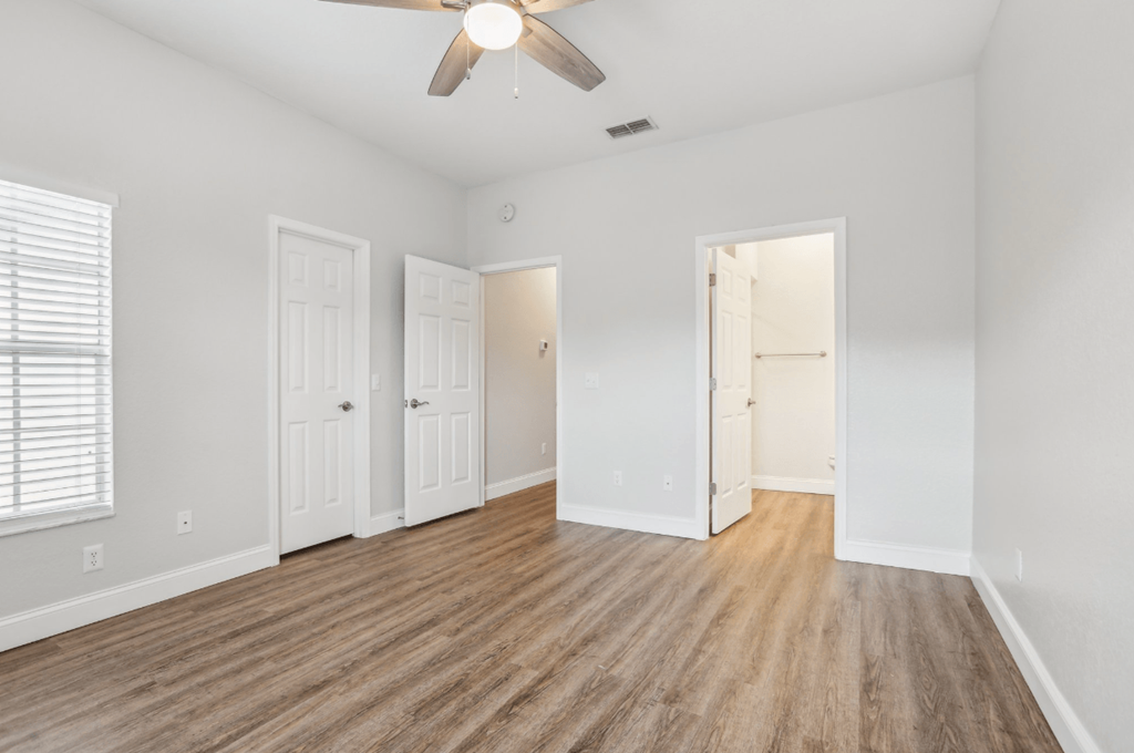A room with a ceiling fan and wooden flooring.